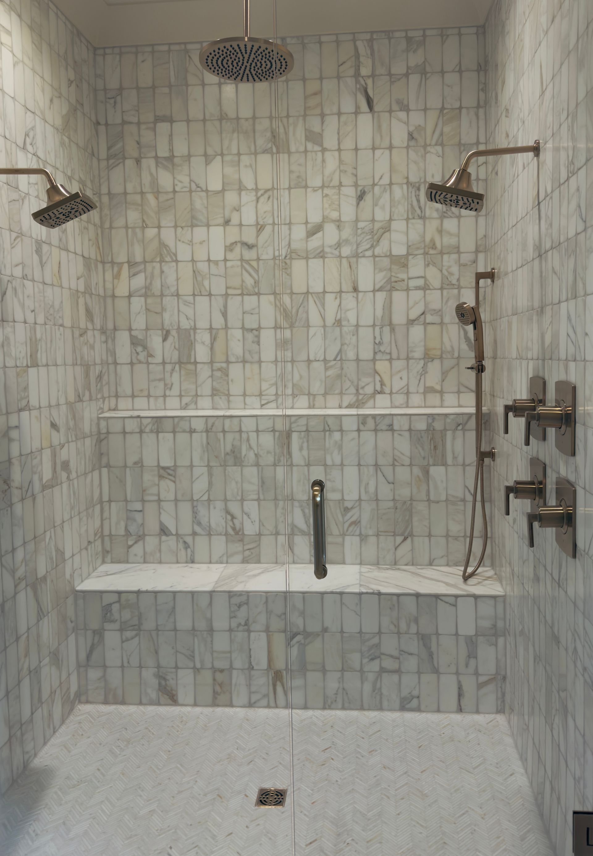 Tile shower corner with round showerhead, wall mixer, and decorative gray mosaic border