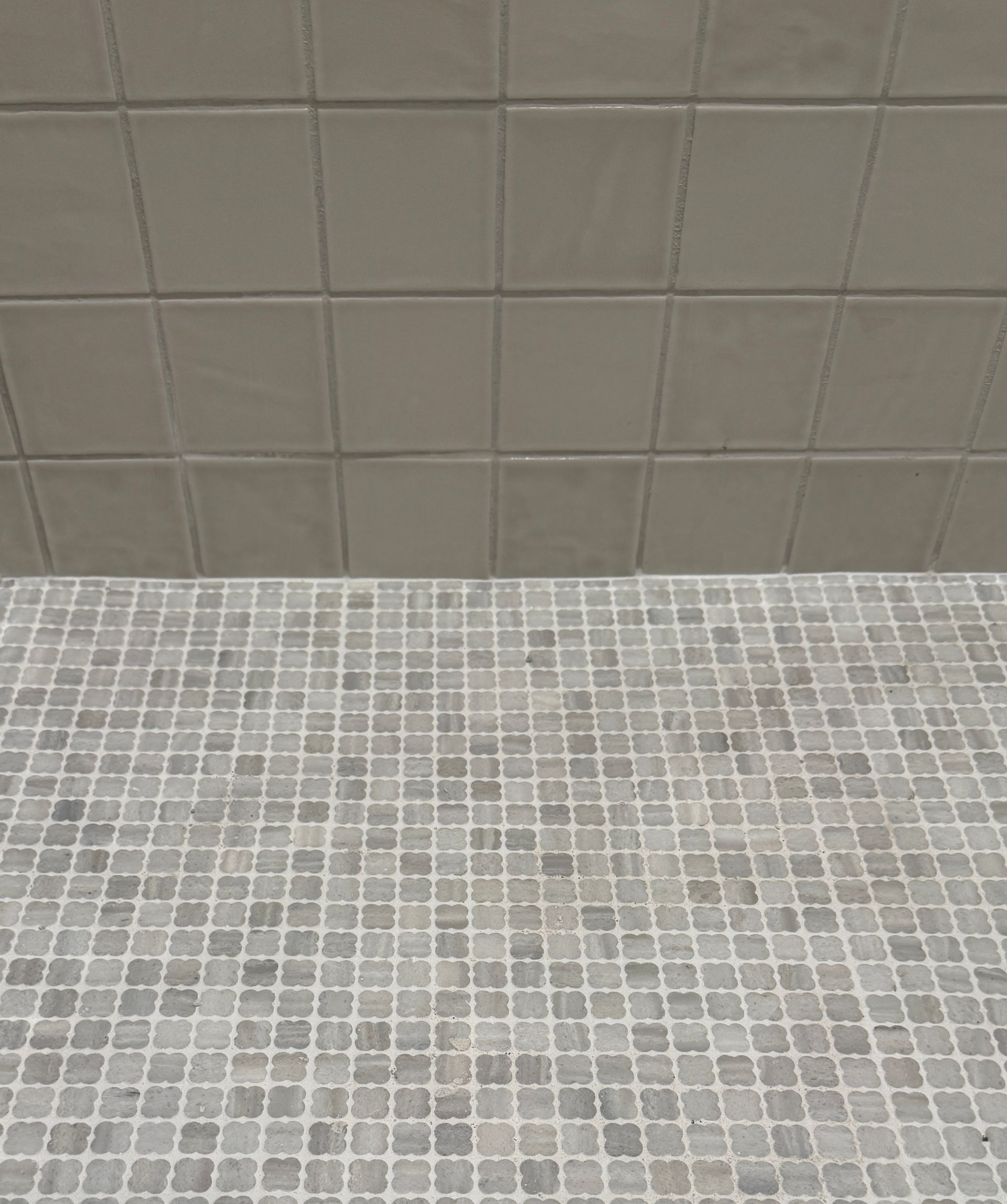 Modern bathroom vanity with round mirror, white bowl sink, and beige patterned tile wall.