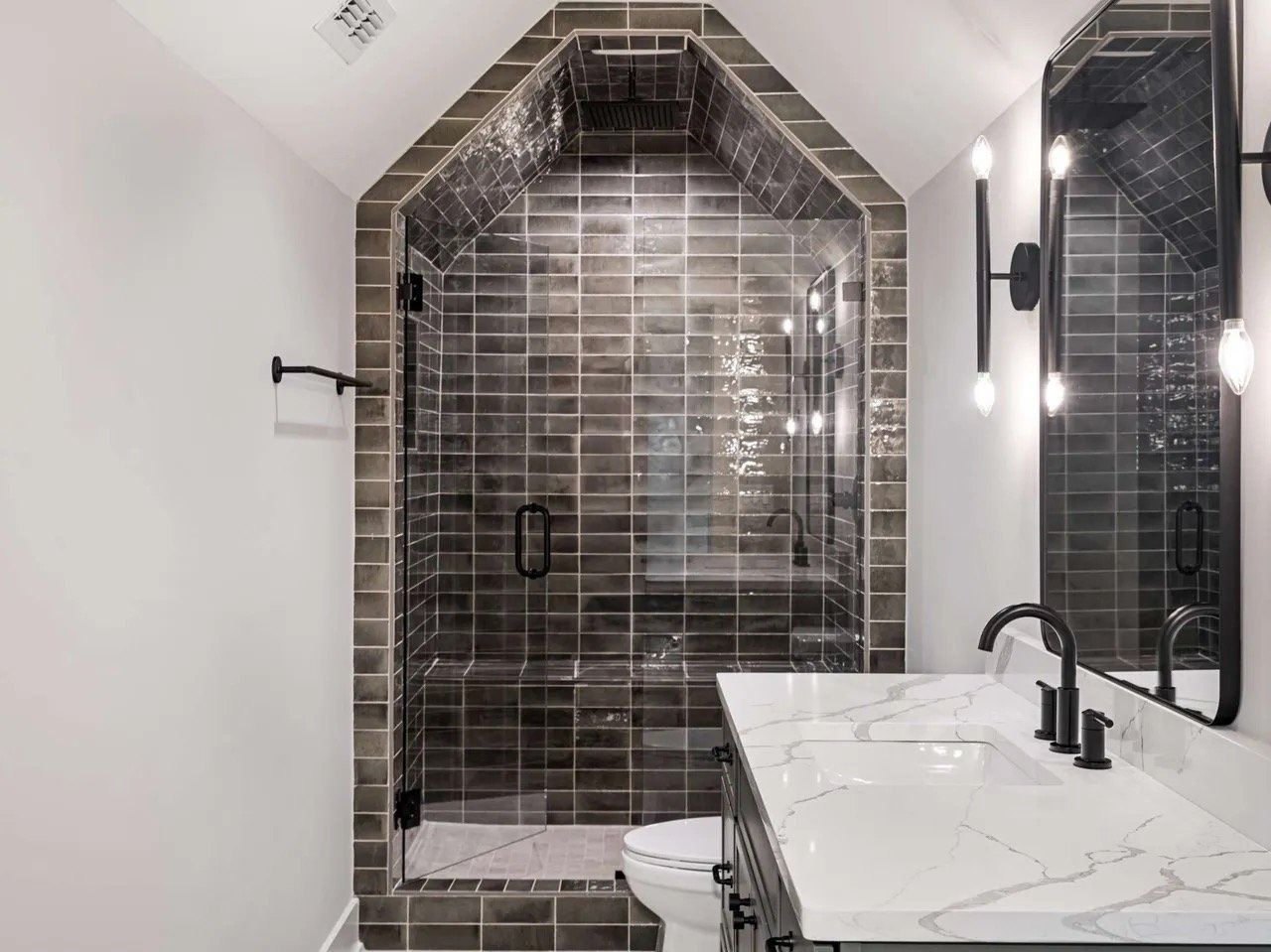 Modern bathroom with black tiled walk-in shower and marble vanity top