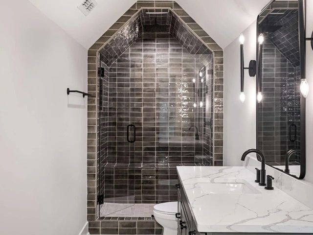 Modern bathroom with tiled shower, marble vanity, and large mirror