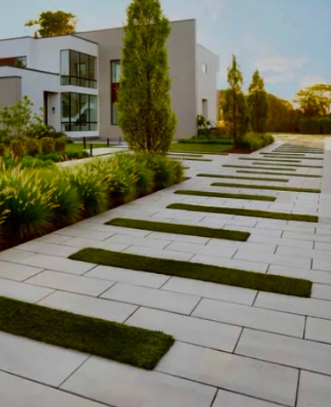 Modern house with a landscaped walkway of white pavers and green grass strips at sunset