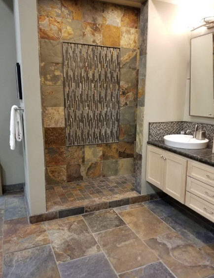 Tiled bathroom with stone shower nook, granite vanity, and beige cabinets and floor tiles