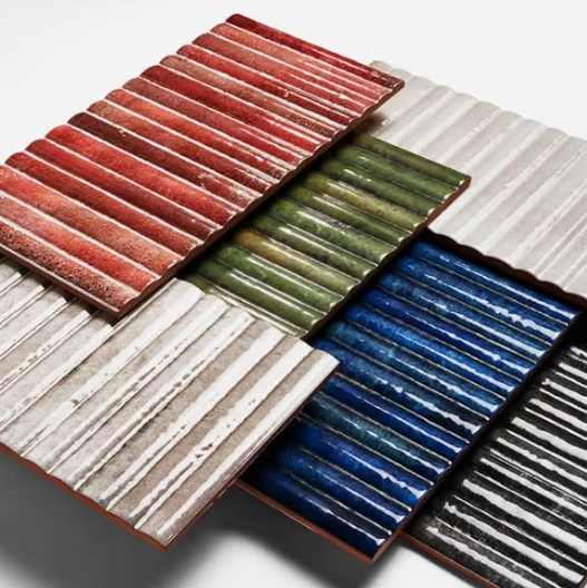 Five corrugated metal roofing panels in red, green, white, blue, and black arranged in a stack