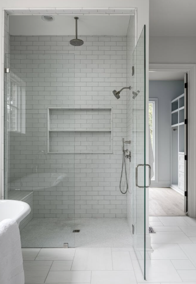 Modern white tiled bathroom with glass shower, rainfall head, built-in niche, and handheld showerhead