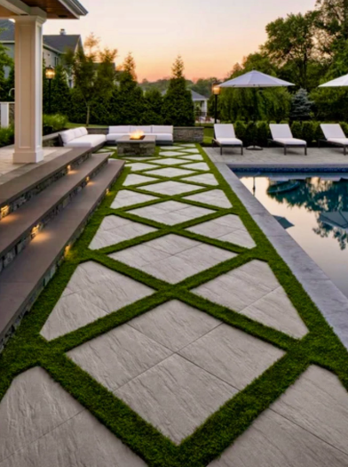 Modern backyard patio with geometric stone walkway, green grass inlays, and a pool at sunset