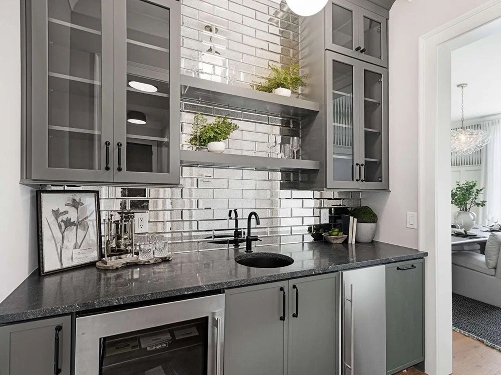 Modern kitchen with gray cabinets, black countertop, white subway tile backsplash, and stainless appliances