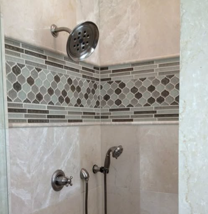 Tile shower corner with round showerhead, wall mixer, and decorative gray mosaic border