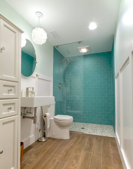 Modern bathroom with turquoise tile shower, white sink and toilet, and wood-look floor