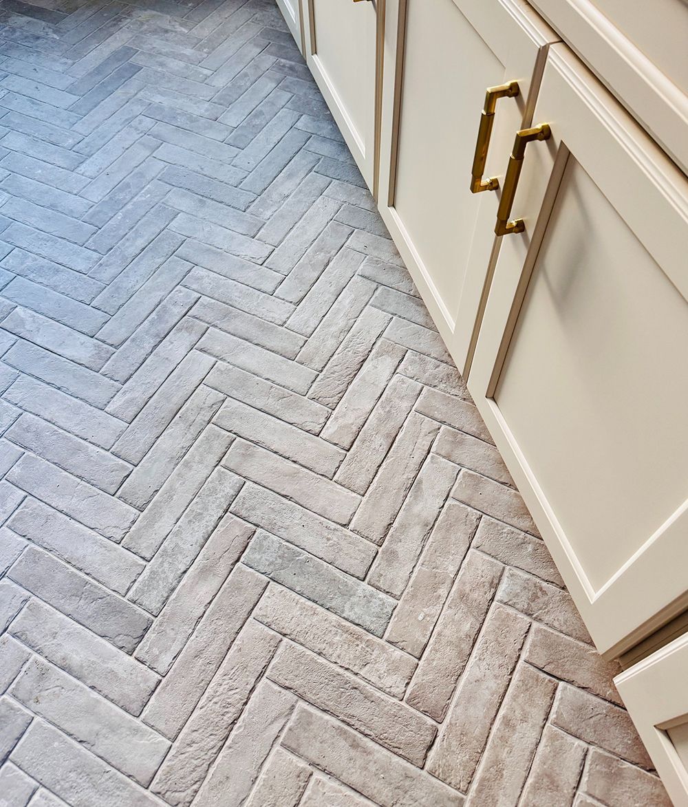 Light gray herringbone carpet beside white cabinets with gold handles
