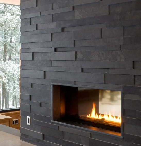 Modern dark stone fireplace with a small fire burning in a contemporary room