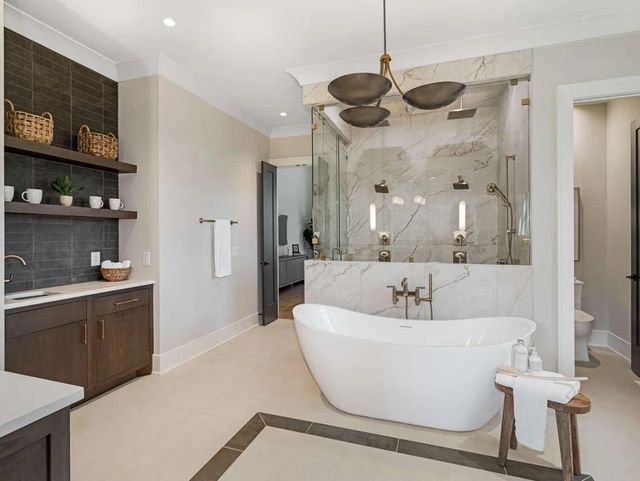 Luxurious bathroom with freestanding tub, marble shower, and dark wood vanity.