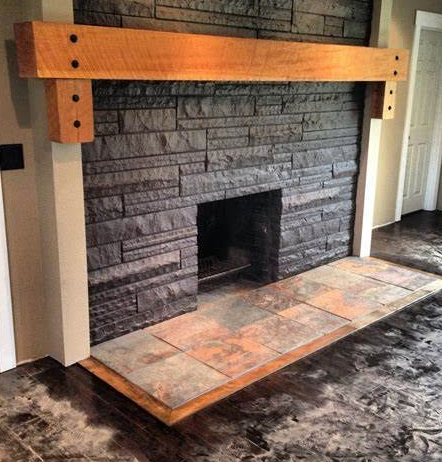 Stone fireplace with a black hearth and a thick wooden mantel over a tiled base.