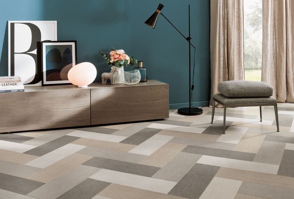 Modern living room with teal wall, low wooden cabinet, floor lamp, chair, and geometric beige-gray rug