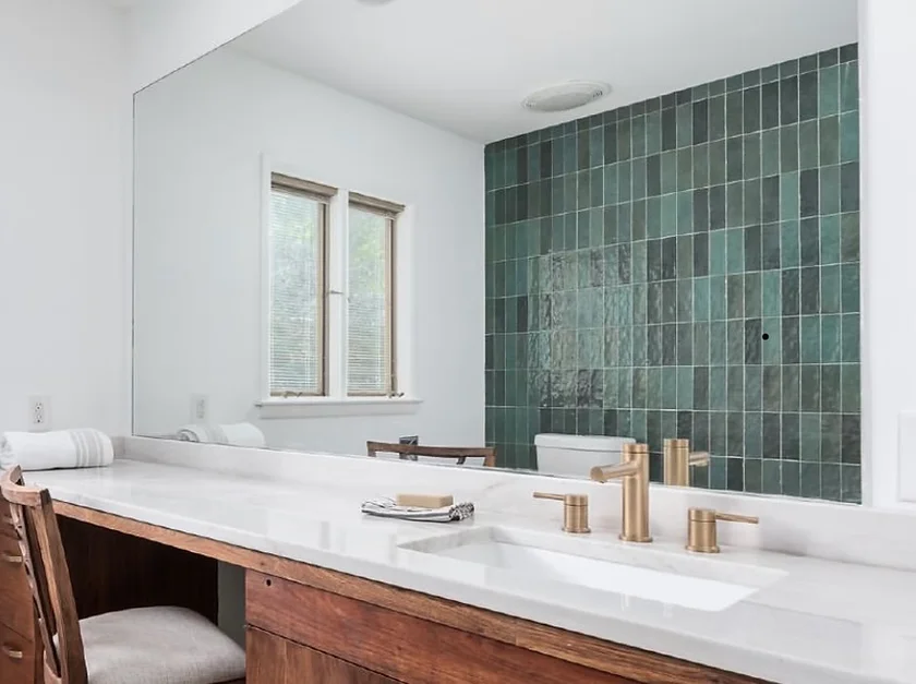 Modern bathroom with a white tub, wood vanity, and green tile accent wall