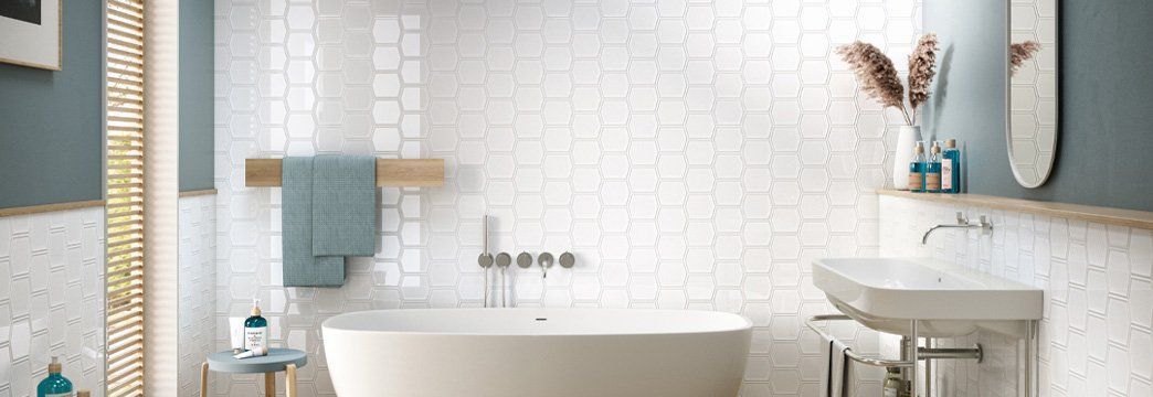 Modern white bathroom with a bathtub, sink, towel rack, and blue accents