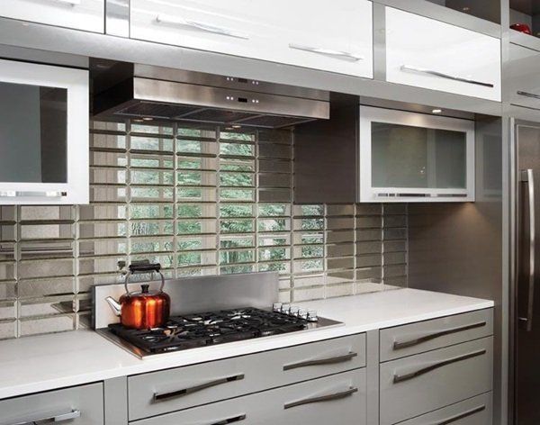 Modern kitchen with white cabinets, gas cooktop, red pot, and tiled backsplash