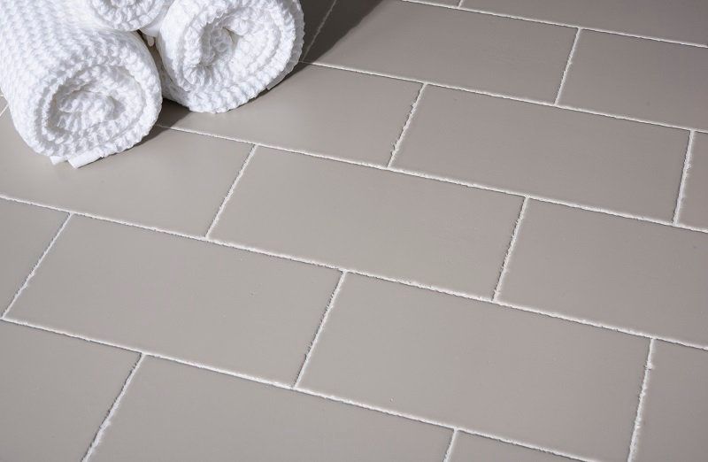 Rolled white towels on a light gray tiled bathroom floor
