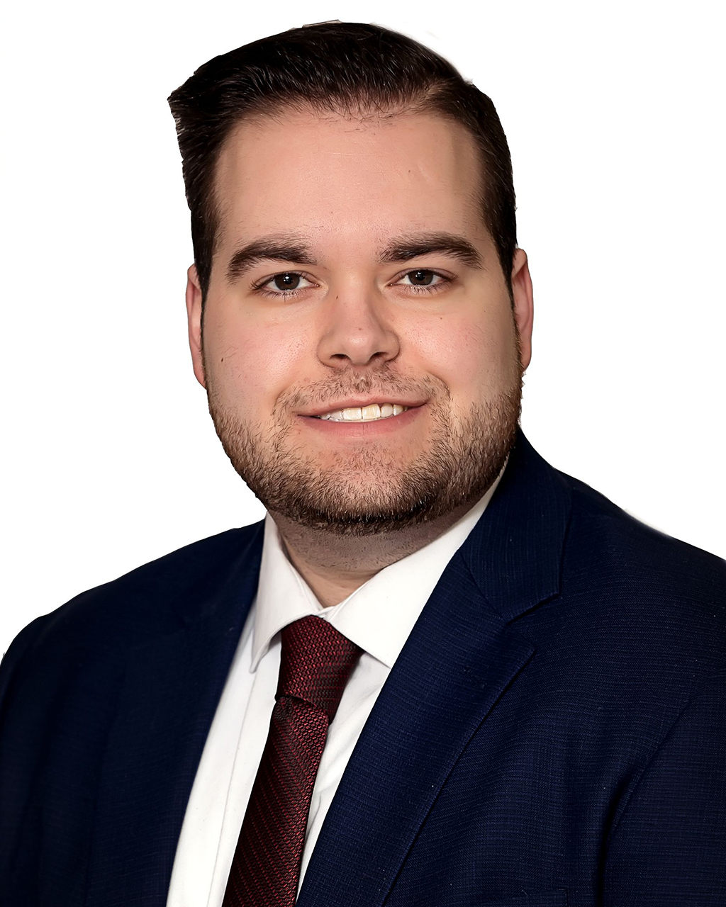 Man in a navy blue suit and burgundy tie smiling at the camera.