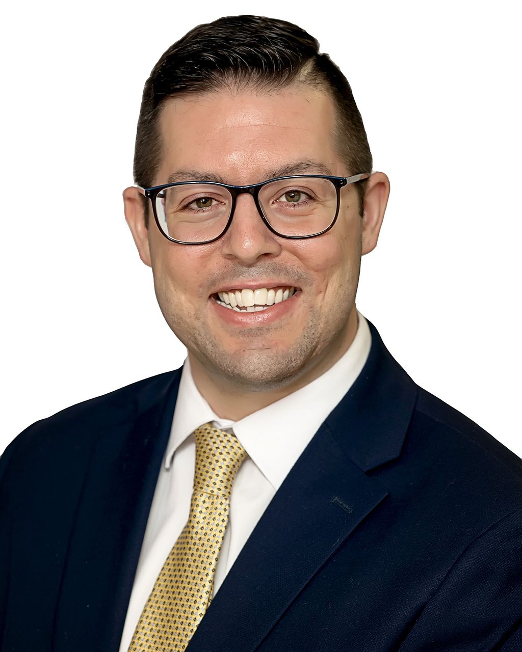 Man in navy suit, glasses, and yellow tie smiles, head and shoulders.