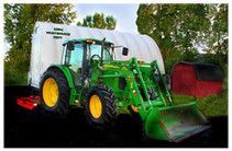 a green bulldozer parked on the road with a red barn house at the background