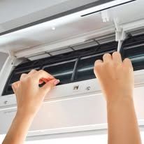 A person is cleaning an air conditioner with a screwdriver.