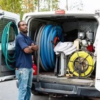 A man is standing in front of a van filled with hose.