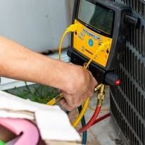 A person is using a digital thermometer to check the temperature of an air conditioner.