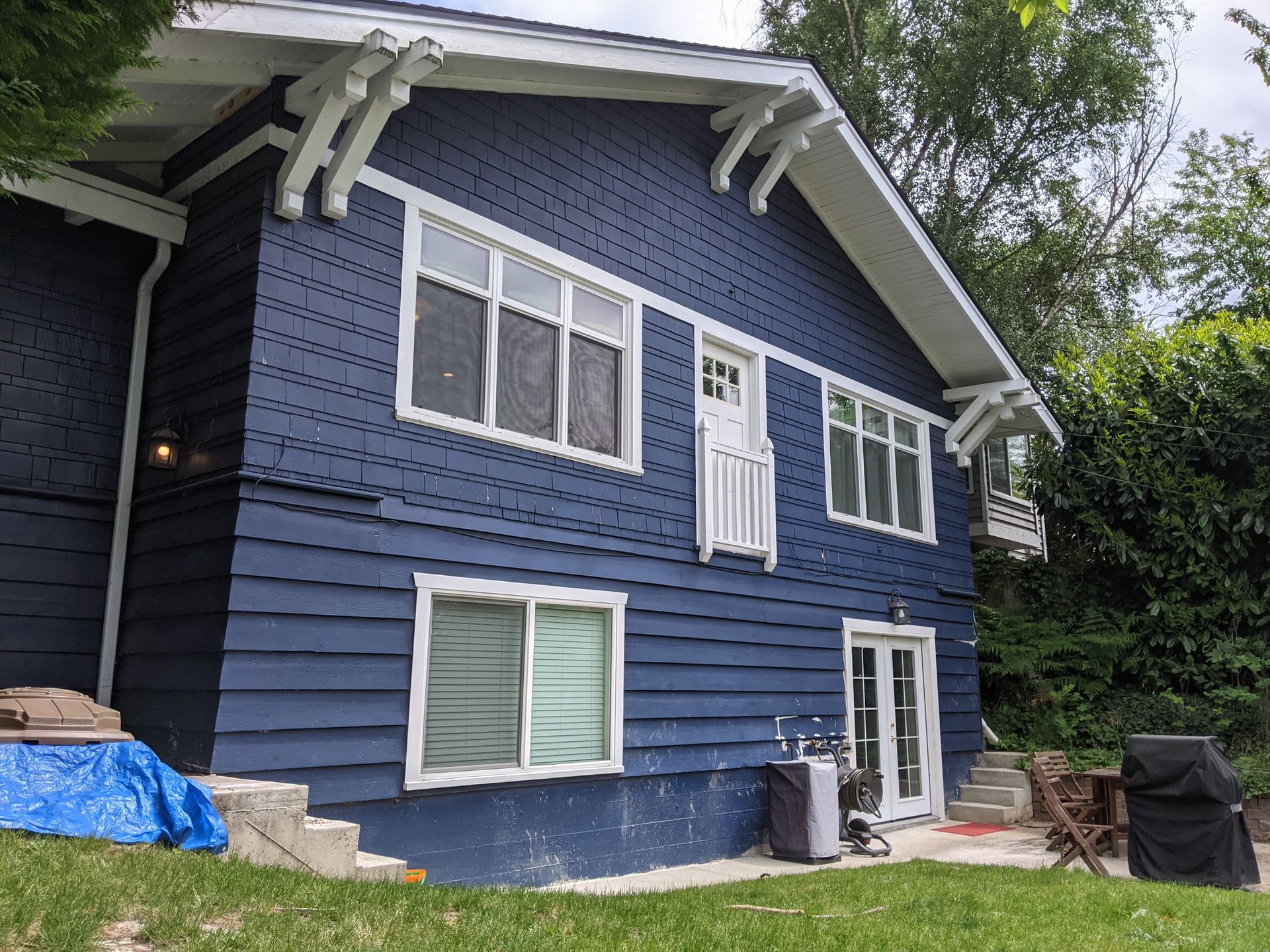 A blue house with white trim is sitting on top of a lush green hillside.