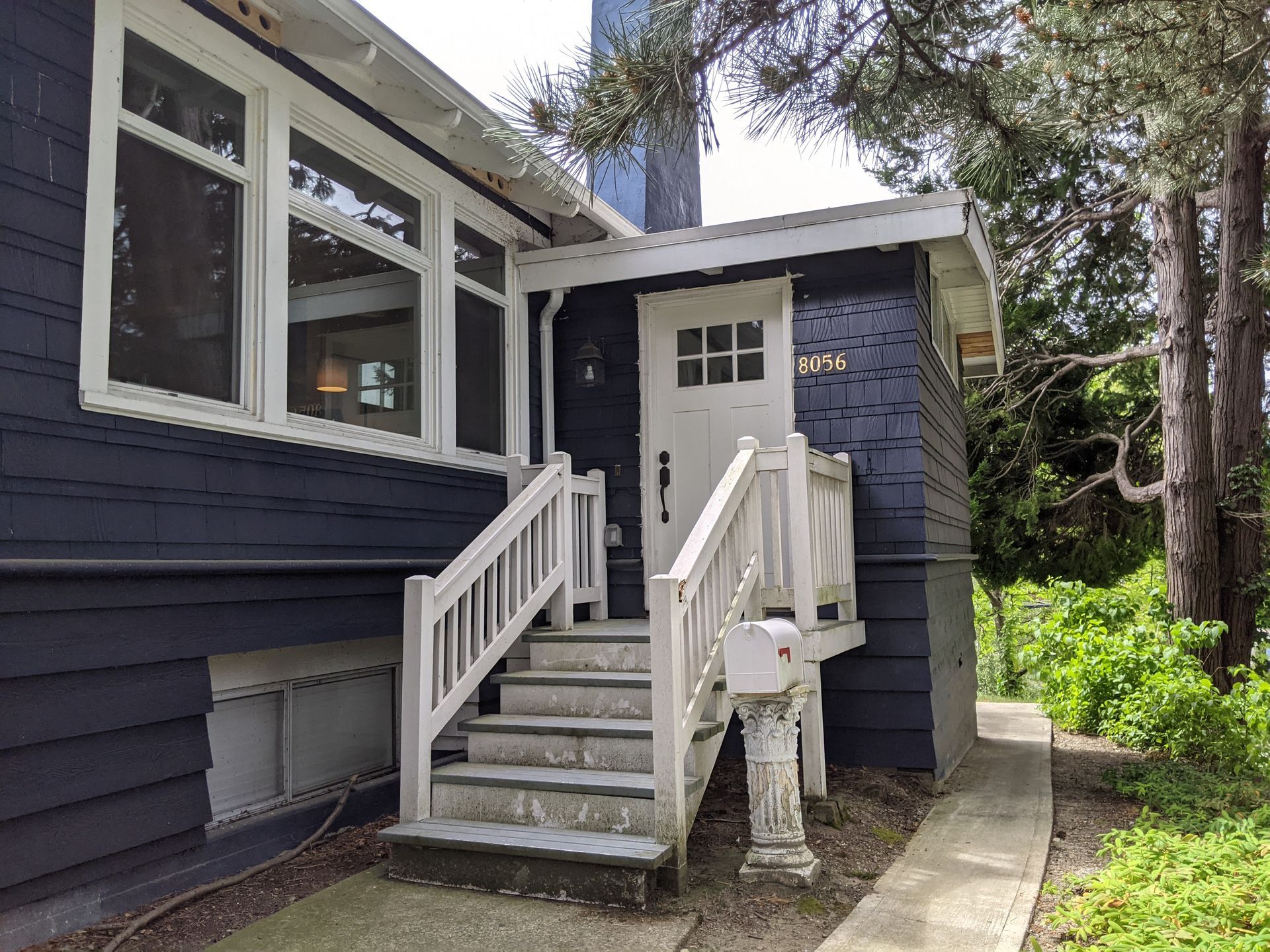 A blue house with white stairs leading up to the front door