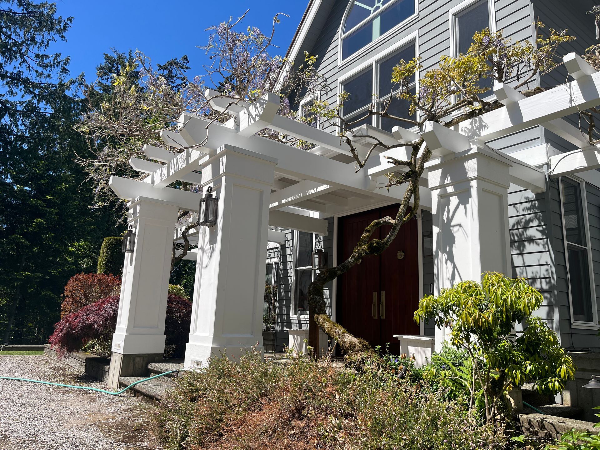 The front of a house with a white pergola and a red door