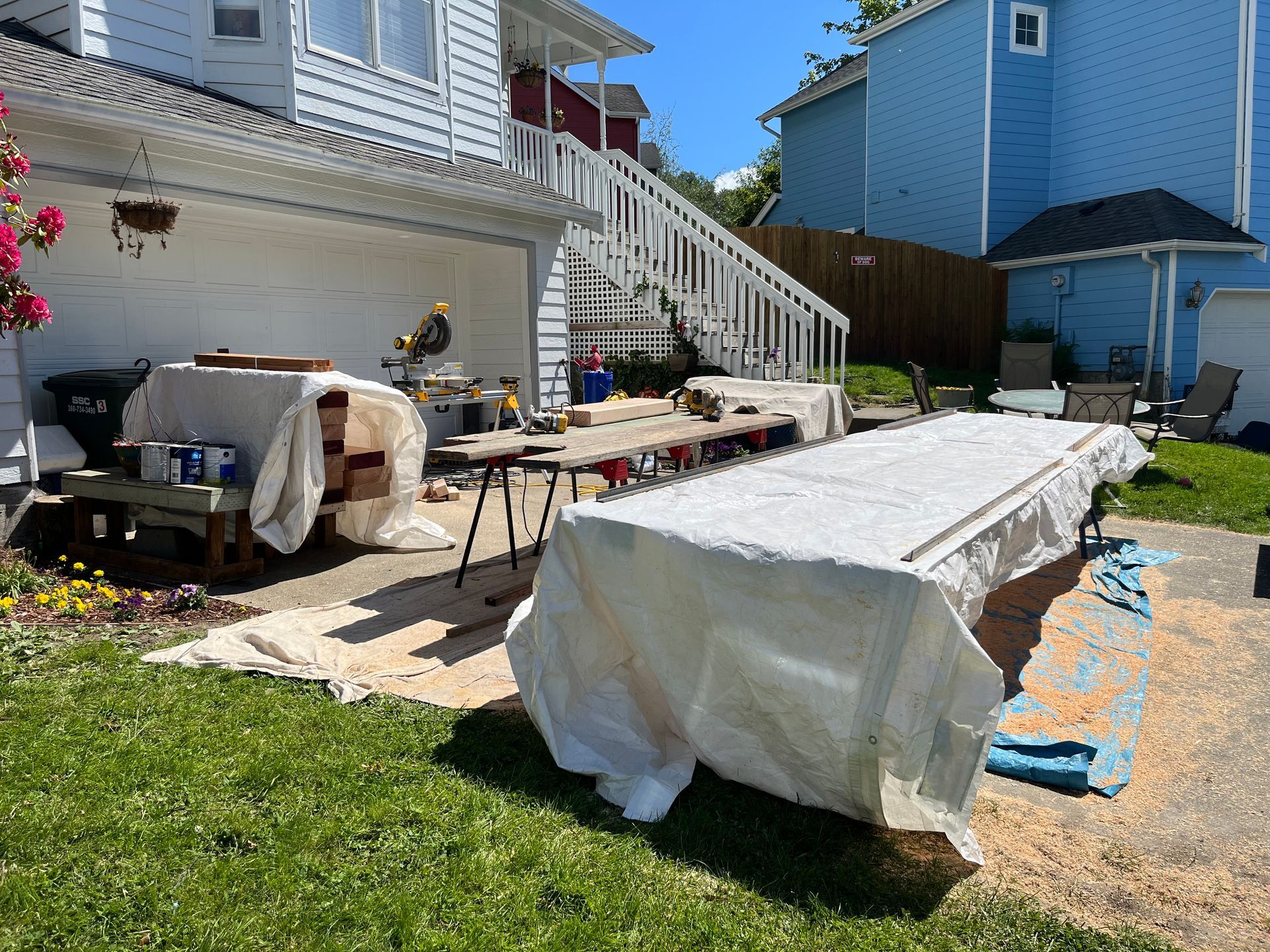 A large white table is sitting in the grass in front of a house.