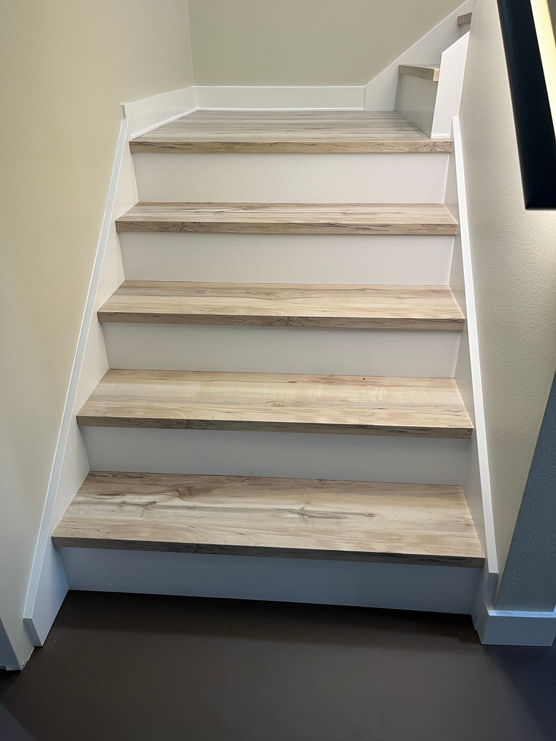 A set of stairs with wooden steps and a white railing.