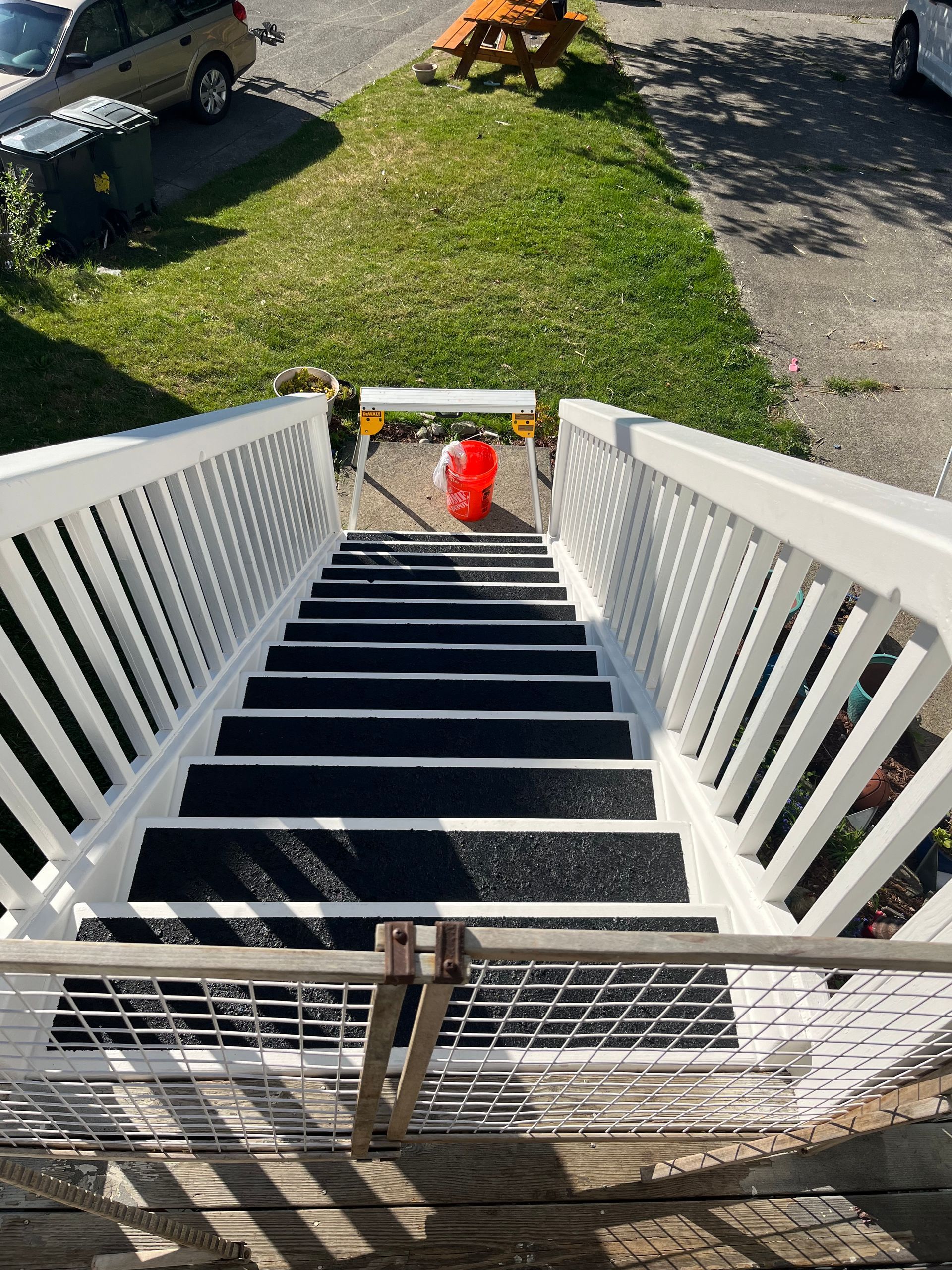 A set of stairs leading up to a house with a white railing and black steps.