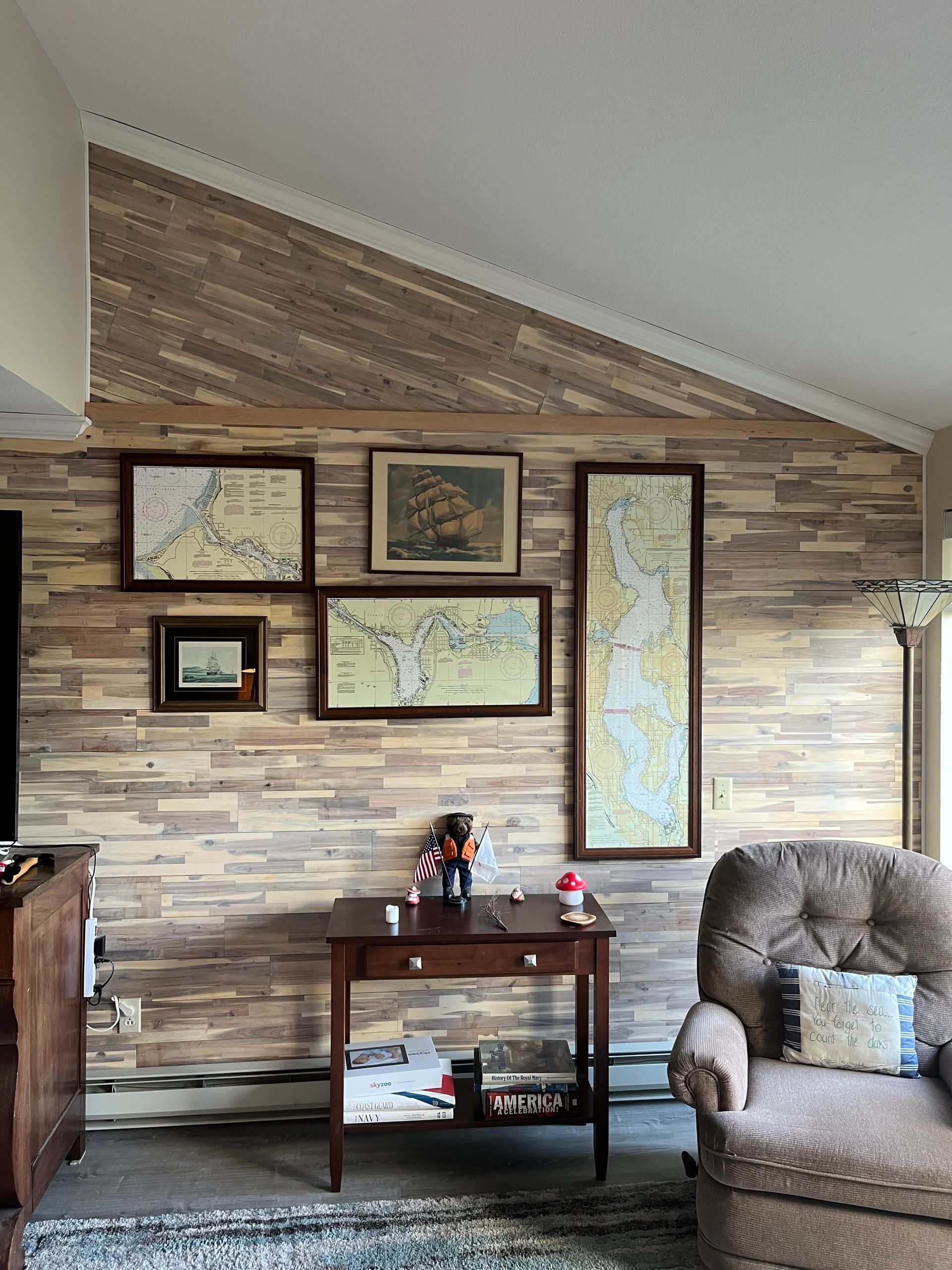 A living room with a wooden wall and maps on the wall.