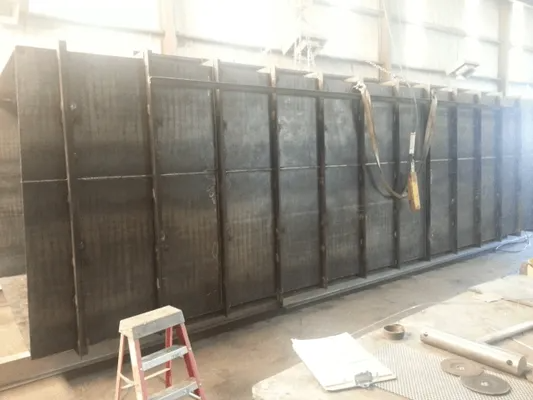 Row of large black metal storage cabinets in a workshop, with a step stool and tools in the foreground