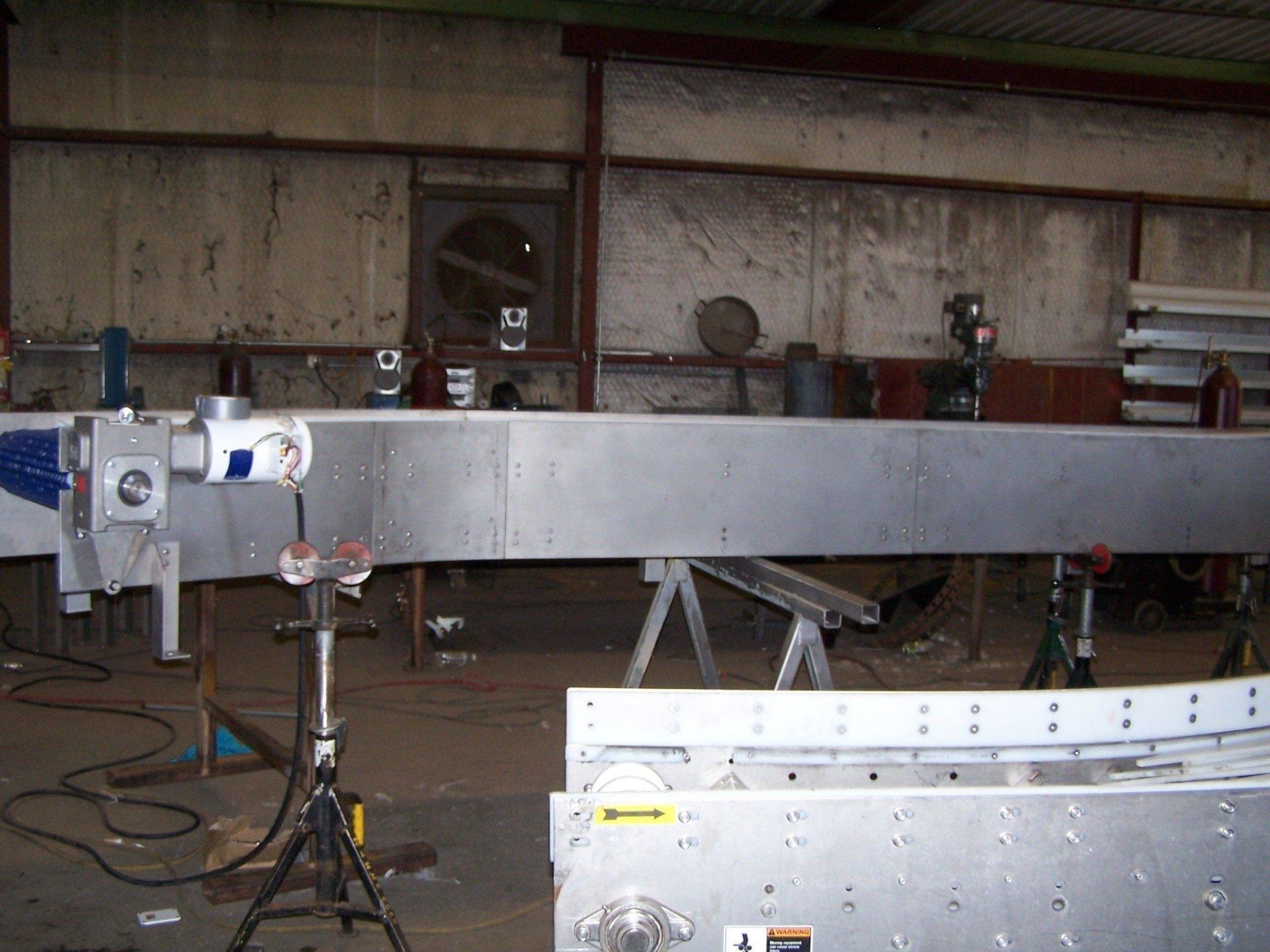 Long metal beam on a workshop floor with clamps and stands in an industrial garage