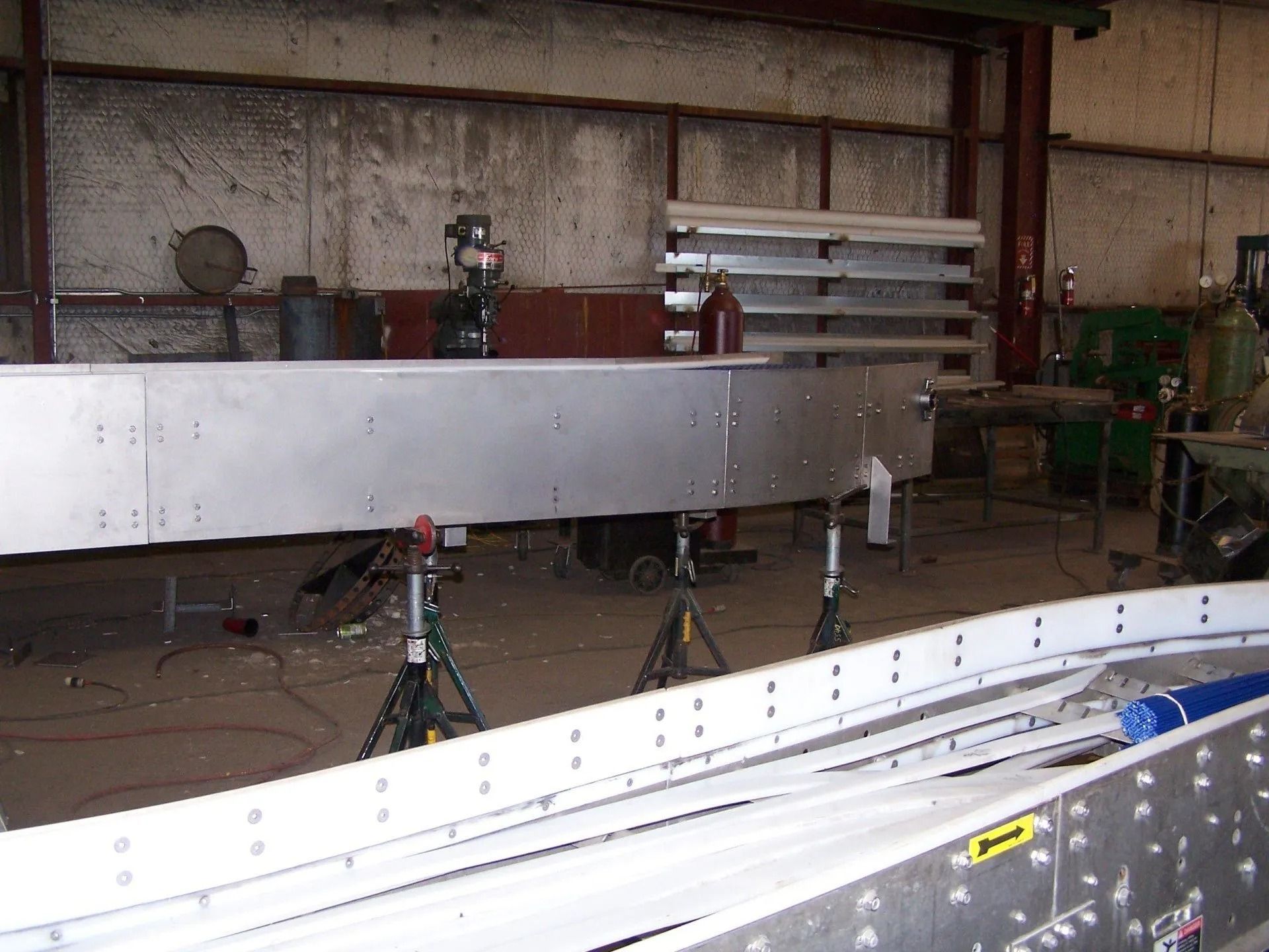 Industrial workshop with long metal panels on stands and tools in the background