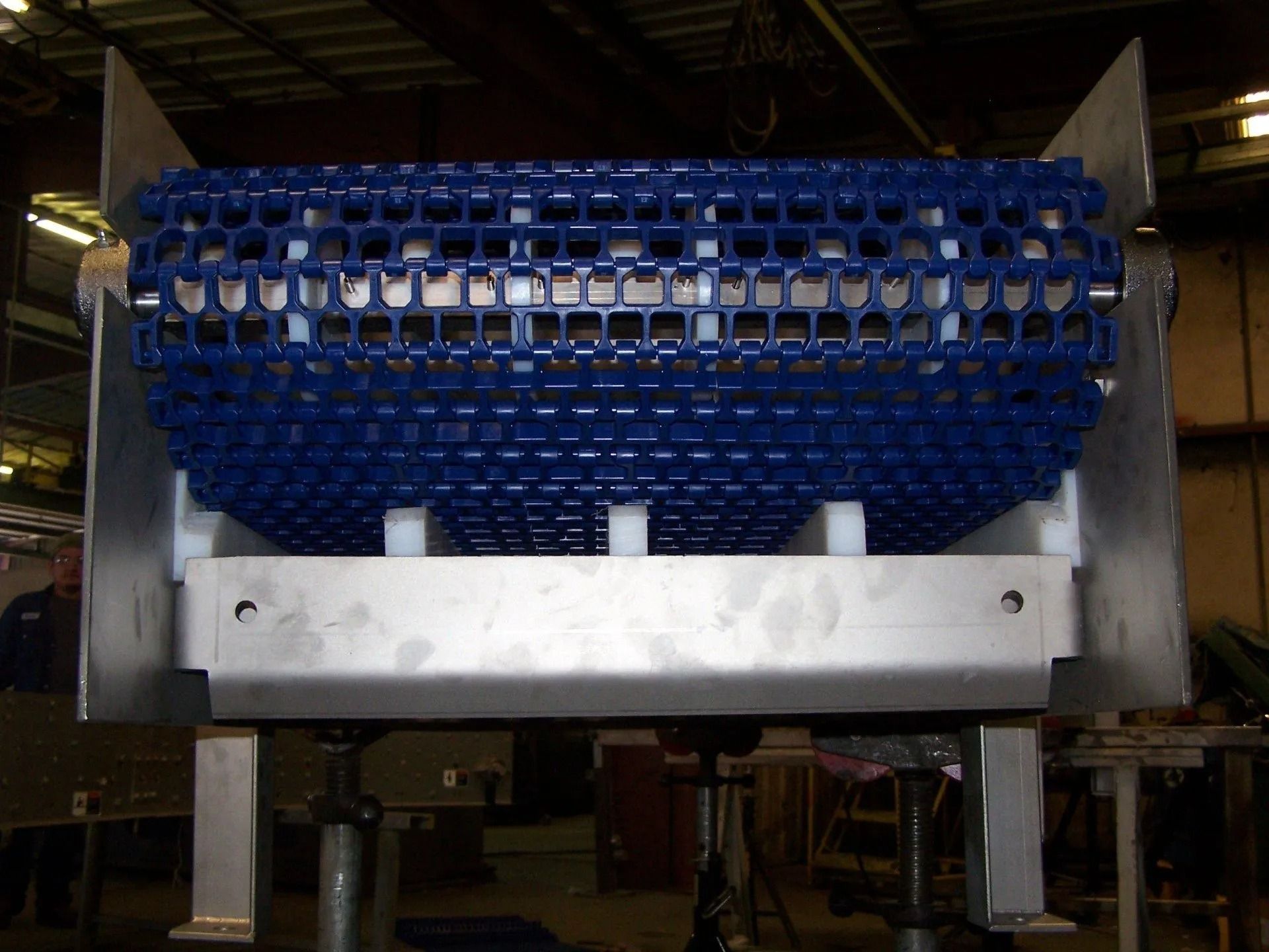 Large blue industrial machine with a perforated cylindrical drum in a factory setting