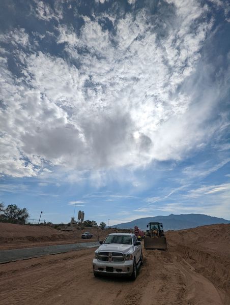 A white truck is parked on the side of a dirt road