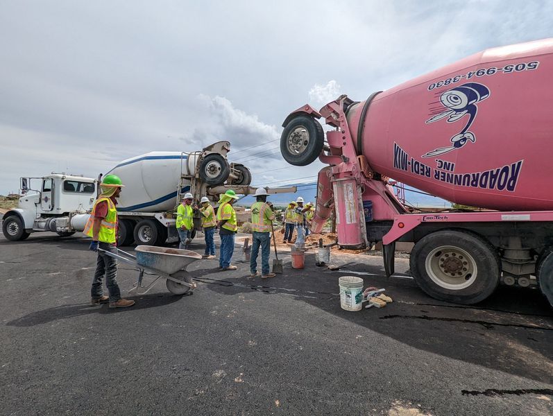 A group of construction workers are standing in front of a pink concrete mixer truck.