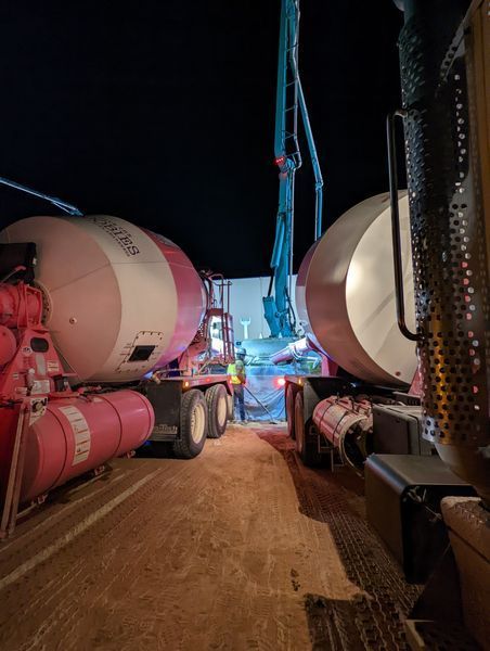 A couple of trucks are parked next to each other on a dirt road at night.