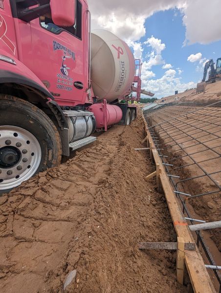 A red concrete truck is driving down a dirt road.