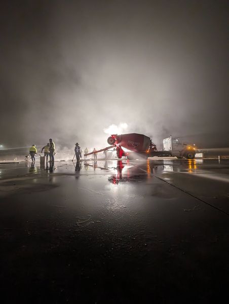 A group of firefighters are spraying water on a runway at night.