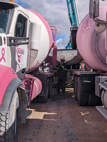 A man is standing in front of a row of pink and white trucks.
