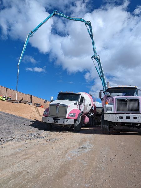 Two trucks are parked next to each other on a dirt road.