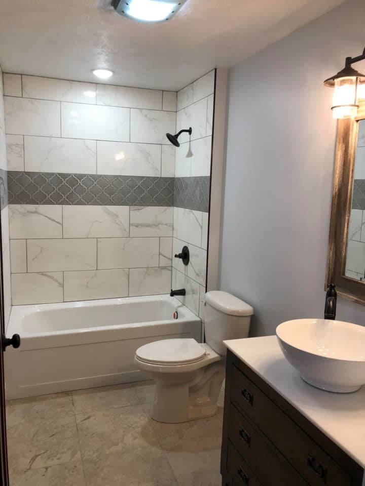A bathroom with a tub , toilet , sink and mirror.