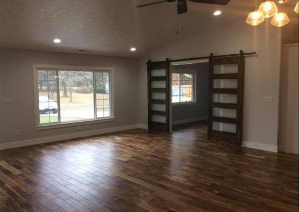 An empty living room with hardwood floors and a sliding barn door.