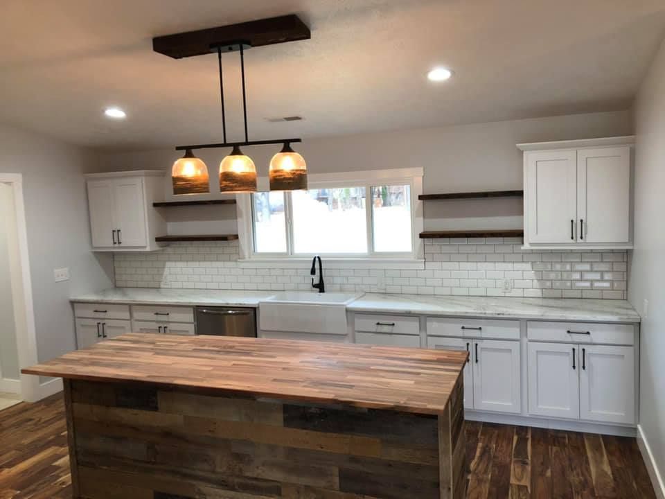 A kitchen with white cabinets and a wooden island