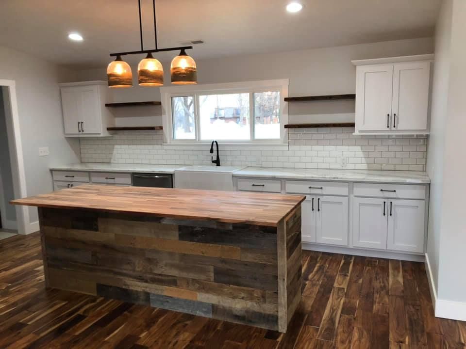 A kitchen with white cabinets and a wooden island in the middle.