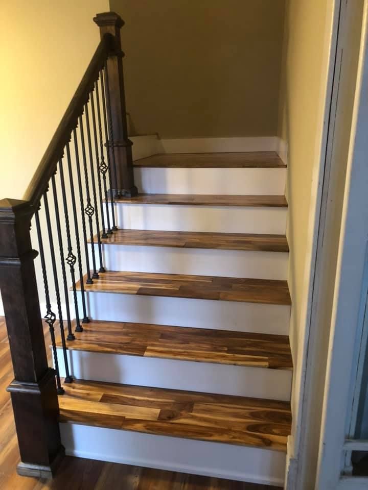A wooden staircase with white steps and a black railing in a house.